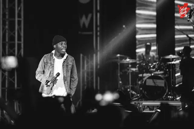 Paddy Daniel on stage under white spotlights, black and white