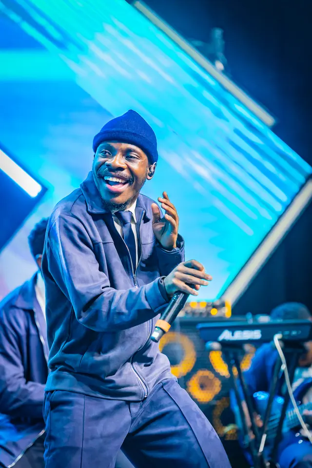 Paddy Daniel singing with energy in front of blue stage beams