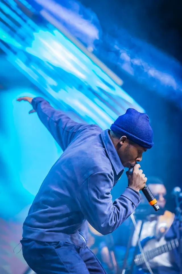Paddy Daniel reaching out to the audience on a blue stage