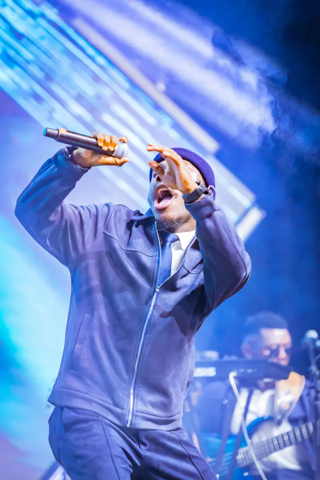 Paddy Daniel singing with his arm raised on a blue stage
