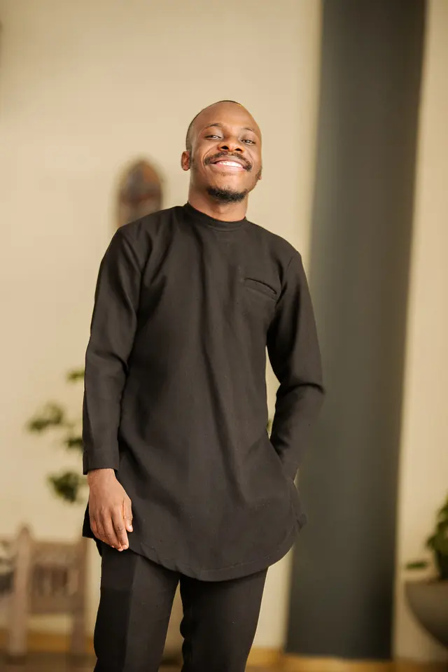 Paddy Daniel in a black kaftan in a warm room