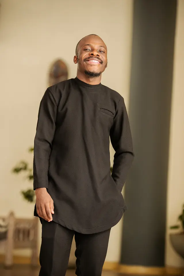 Paddy Daniel in a black kaftan with a relaxed smile