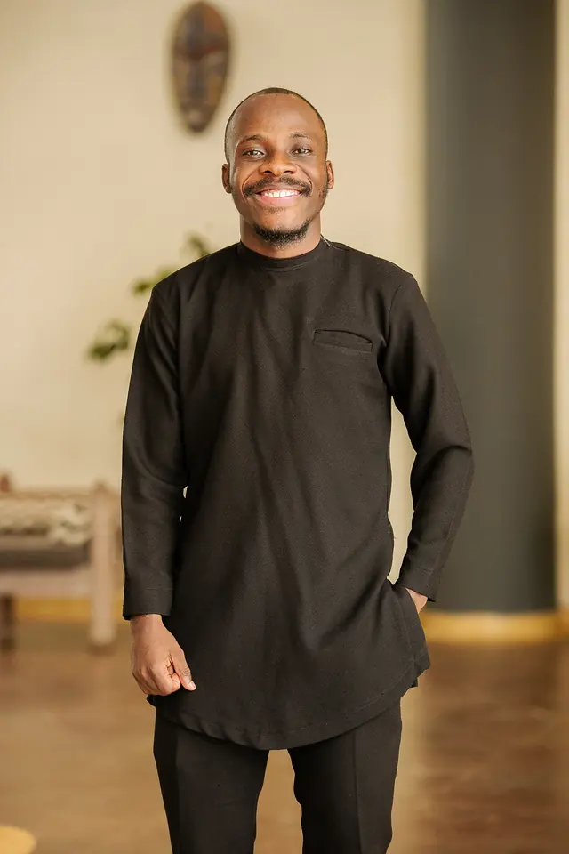 Paddy Daniel in a black kaftan, hands together