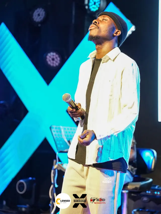 Paddy Daniel singing in front of a large X-shaped light sculpture
